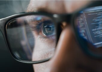 IT professional monitoring security applications, closeup on their eyes and glasses.