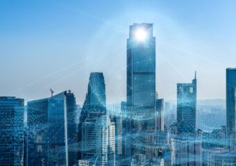 City skyline image in daylight, with sun reflecting off top of one building, city connected by 5G technology.