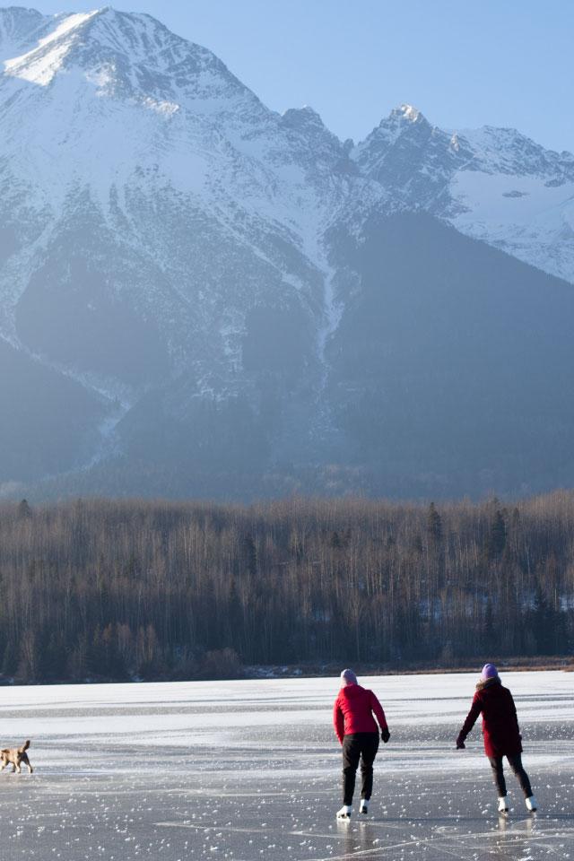 Two people figure skating outside in front of mountains