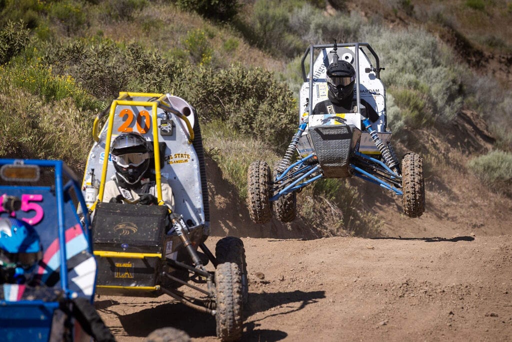 Three baja carts race on a dirt track