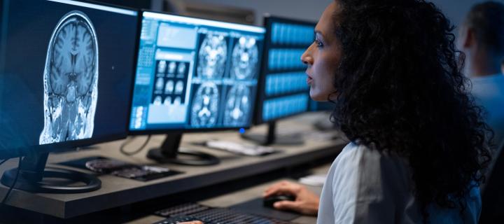 Side view of female radiologist looking at an MRI image of the brain on her computer