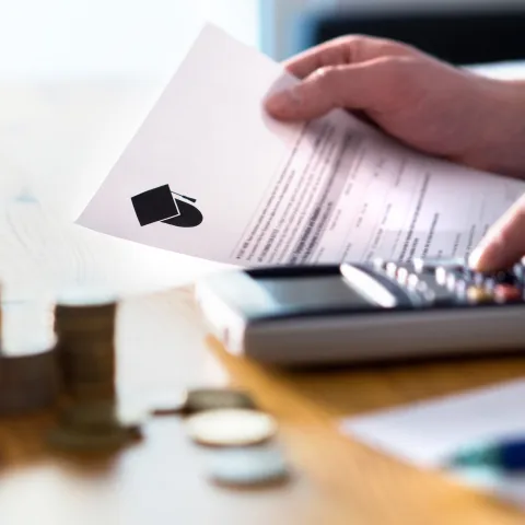 A person holding a document while using a calculator. 