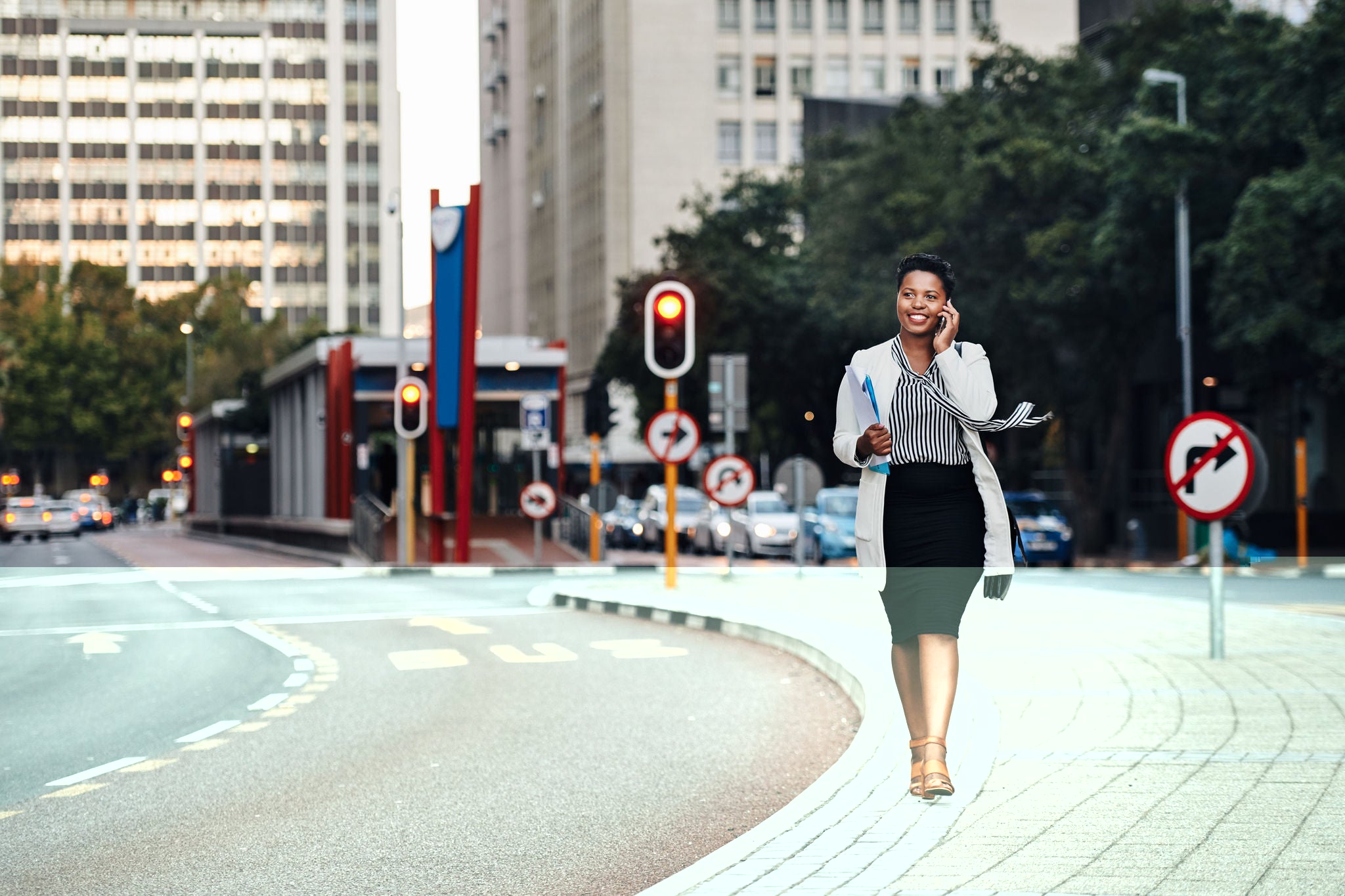 Smiling businesswoman walking while talking on mobile phone