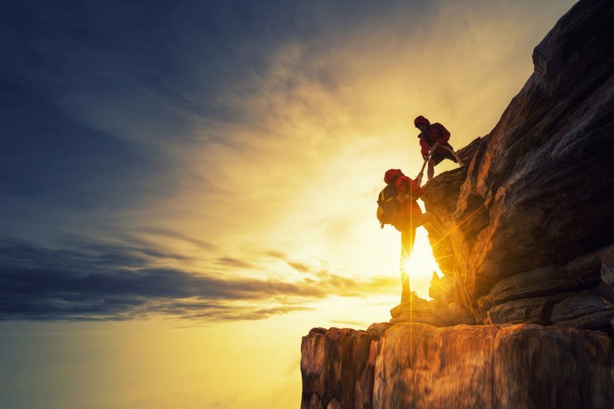 Mountaineer helping another climber reach the top