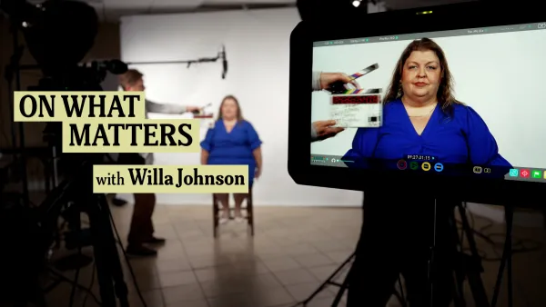 Willa Johnson in a blue dress sits on a stool in a studio, facing the camera. The text "ON WHAT MATTERS with Willa Johnson" is displayed on the left. A crew member holds a clapperboard, and the scene is visible on a monitor in the foreground.