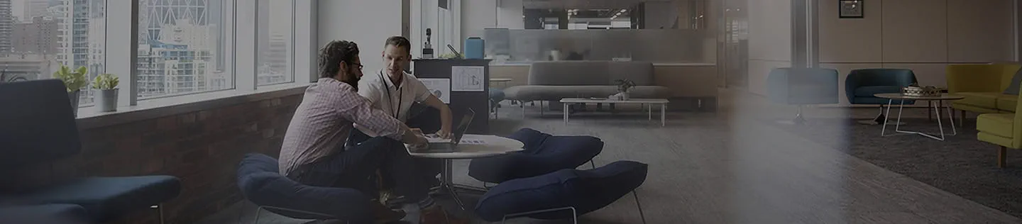 Two colleagues having a discussion in an open office space.