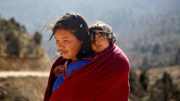 A woman carries her daughter near Punakha; Bhutan strives to balance economic development with its GNH philosophy.