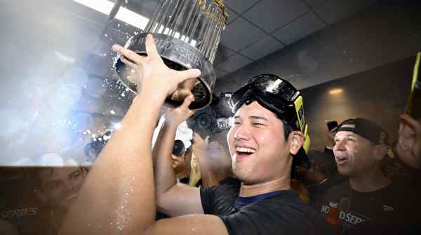 Shohei Ohtani holds up the&nbsp;Commissioner's Trophy, given to World Series champions, while celebrating with his teammates.