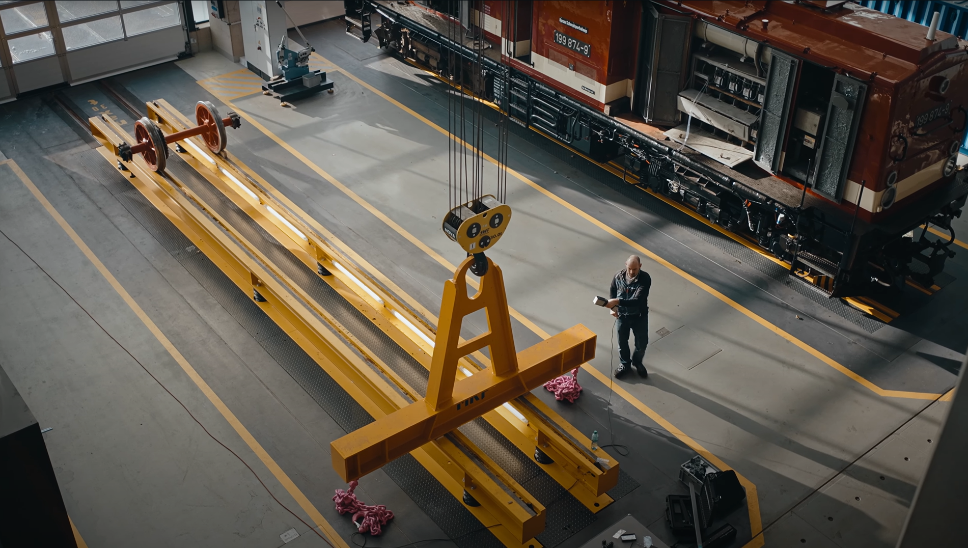 A man in a locomotive workshop 3D scanning a big yellow part