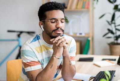 millennial aged man relaxing with eyes close at office desk