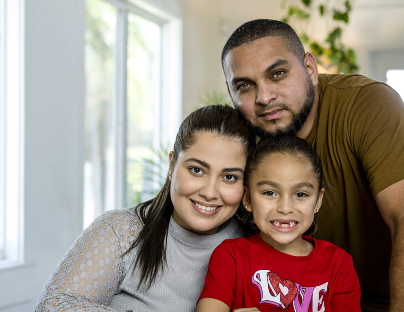 portrait of hispanic family with mom, dad, and young daughter