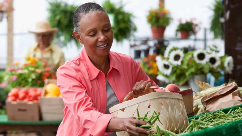 woman selecting produce at farmers market