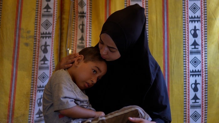 A woman holds her young son in her lap