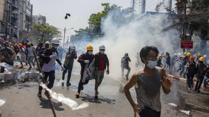 Anti-coup protesters run from teargas deployed by the police during a demonstration in Yangon, Myanmar, March 1, 2021.