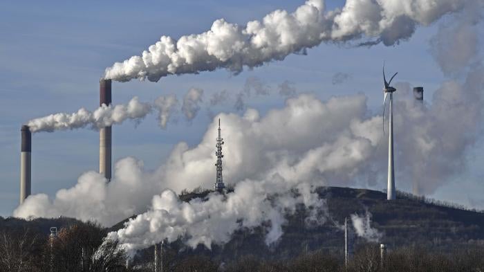 A Uniper coal-fired power plant and a BP refinery steam beside a wind generator in Gelsenkirchen, Germany on Jan. 16, 2020. © 2020 Martin Meissner/AP Photo