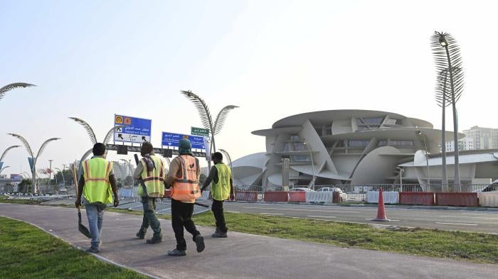 Construction workers walking by the National Museum of Qatar. 