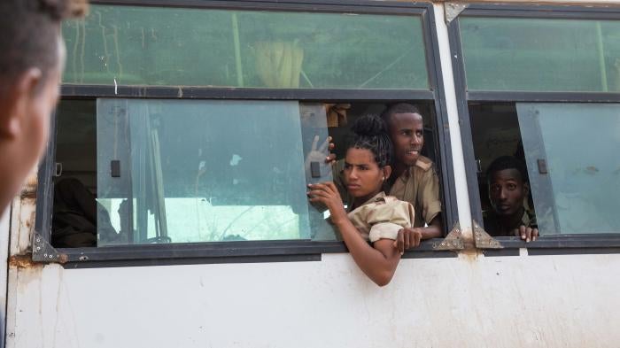 Soldiers lean out of a bus window