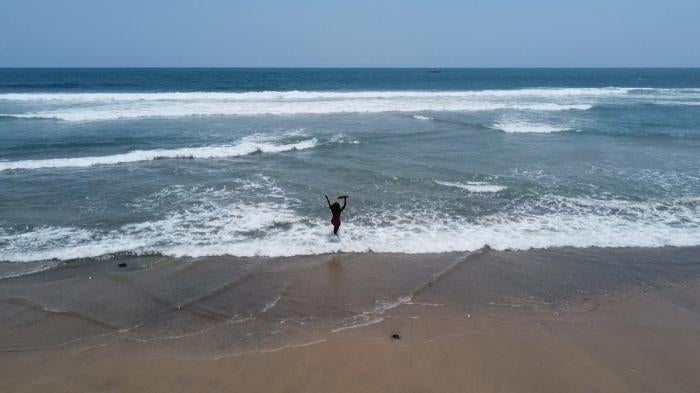 Abena, a young woman with a psychosocial disability, walks along the seashore in Accra, Ghana.