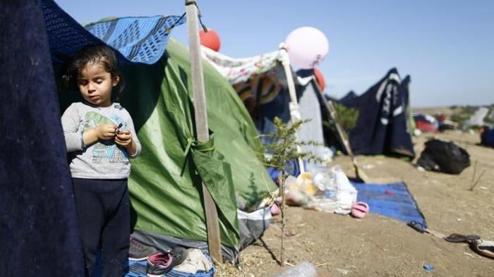 A migrant child stands in a tent on the side of a highway near Edirne, Turkey where hundreds of mostly Syrian migrants have had to wait as Turkish police prevent their bid to cross the border with Greece. 