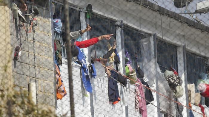 Inmates point from inside of La Modelo prison in Bogota, Colombia, Sunday, March 22, 2020.