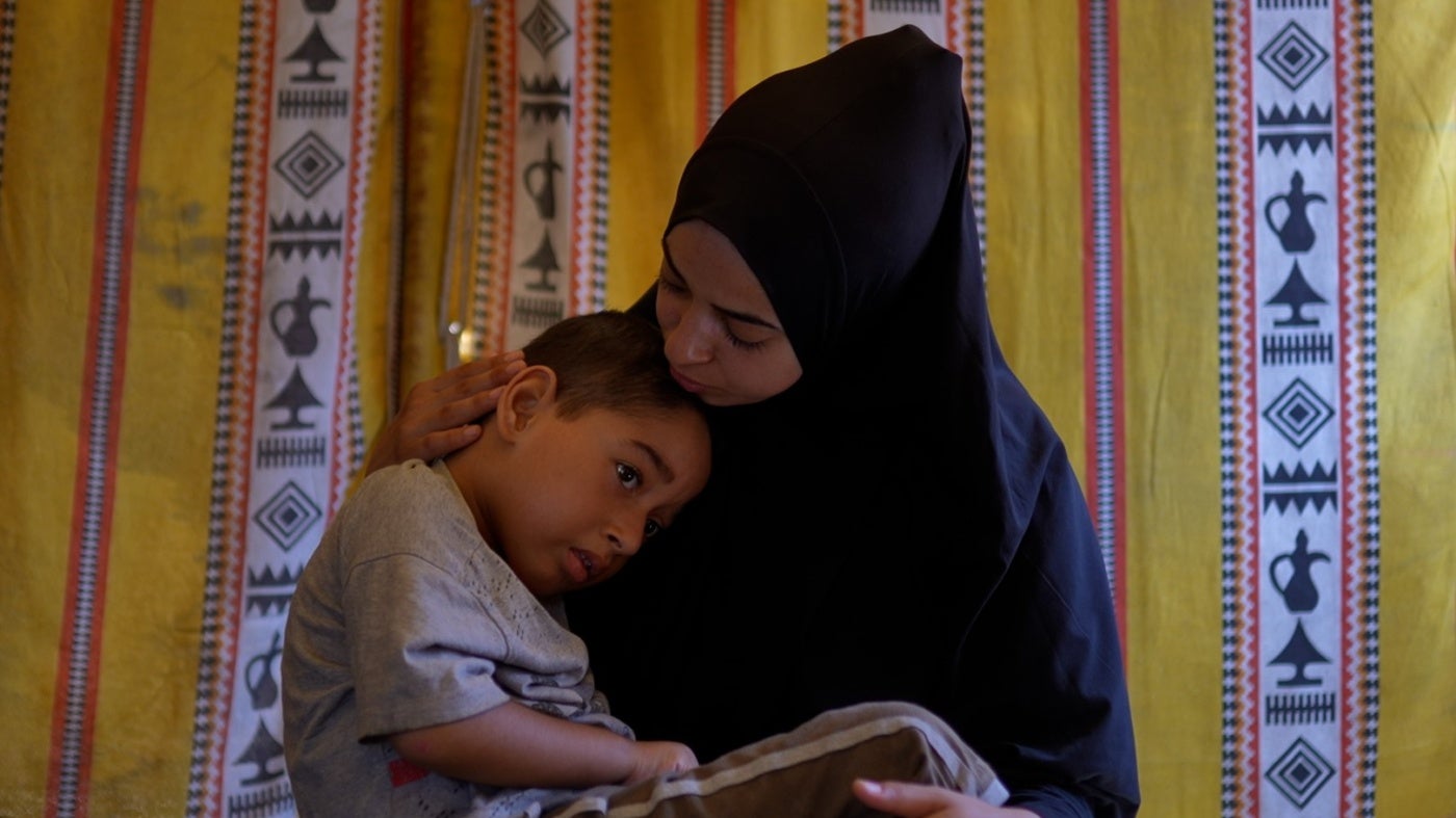 A woman holds her young son in her lap