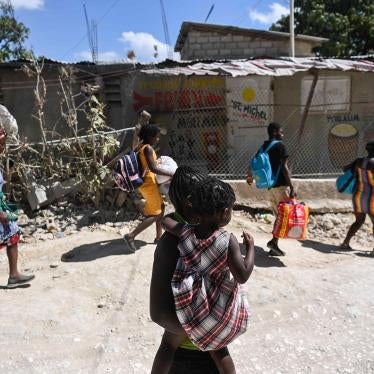 A group of people carry their belongings on a city street 