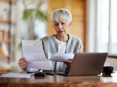 A woman reviews documents at a desk.