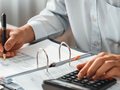 Corporate auditor calculating budget with calculator on his office desk