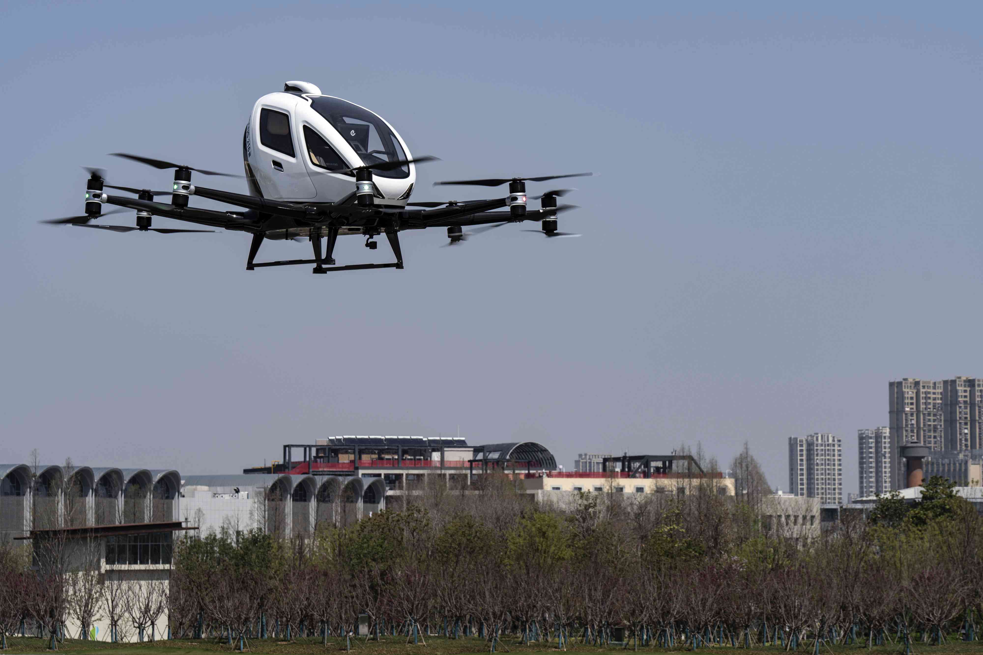 A Ehang Holdings passenger-carrying electric unmanned aerial vehicle hovers above trees in Hefei, China.