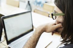 Over shoulder close up of male office worker looking at laptop in office