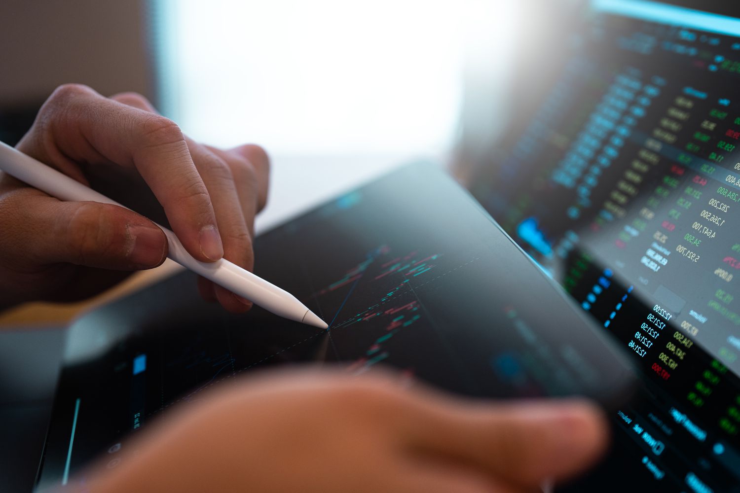 Person sitting at a tablet with a stylus looking at stock data