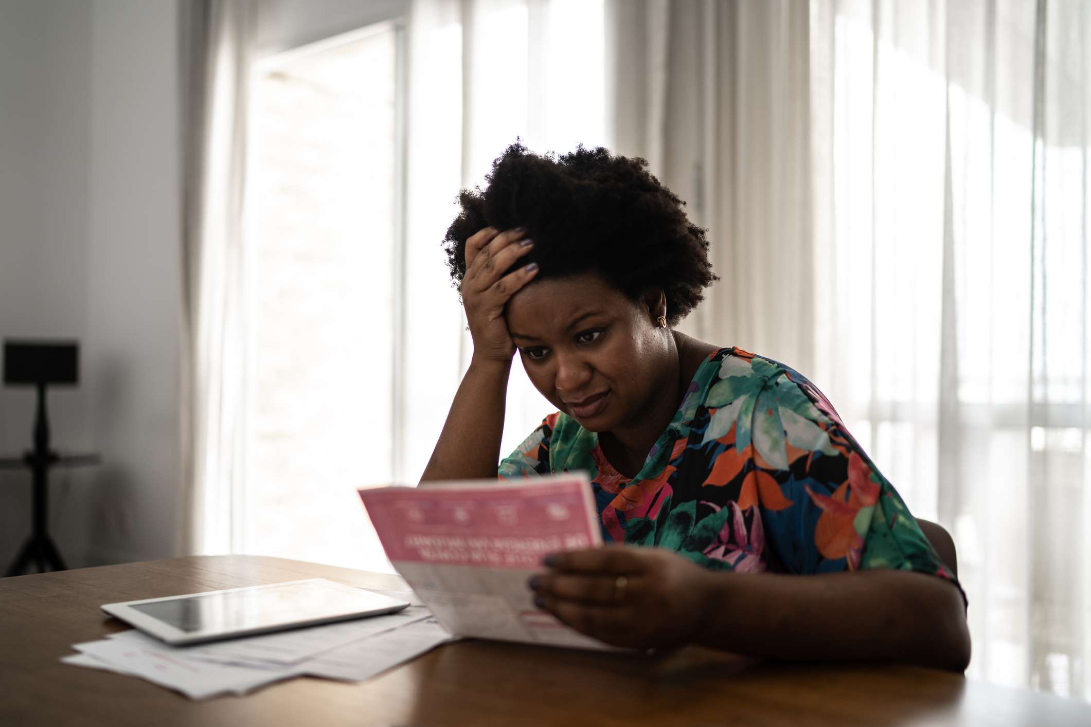 Worried woman looking at past due financial bills at home