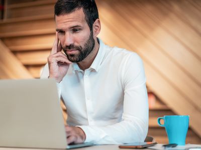 Man in his 30s seriously studying something on his laptop 