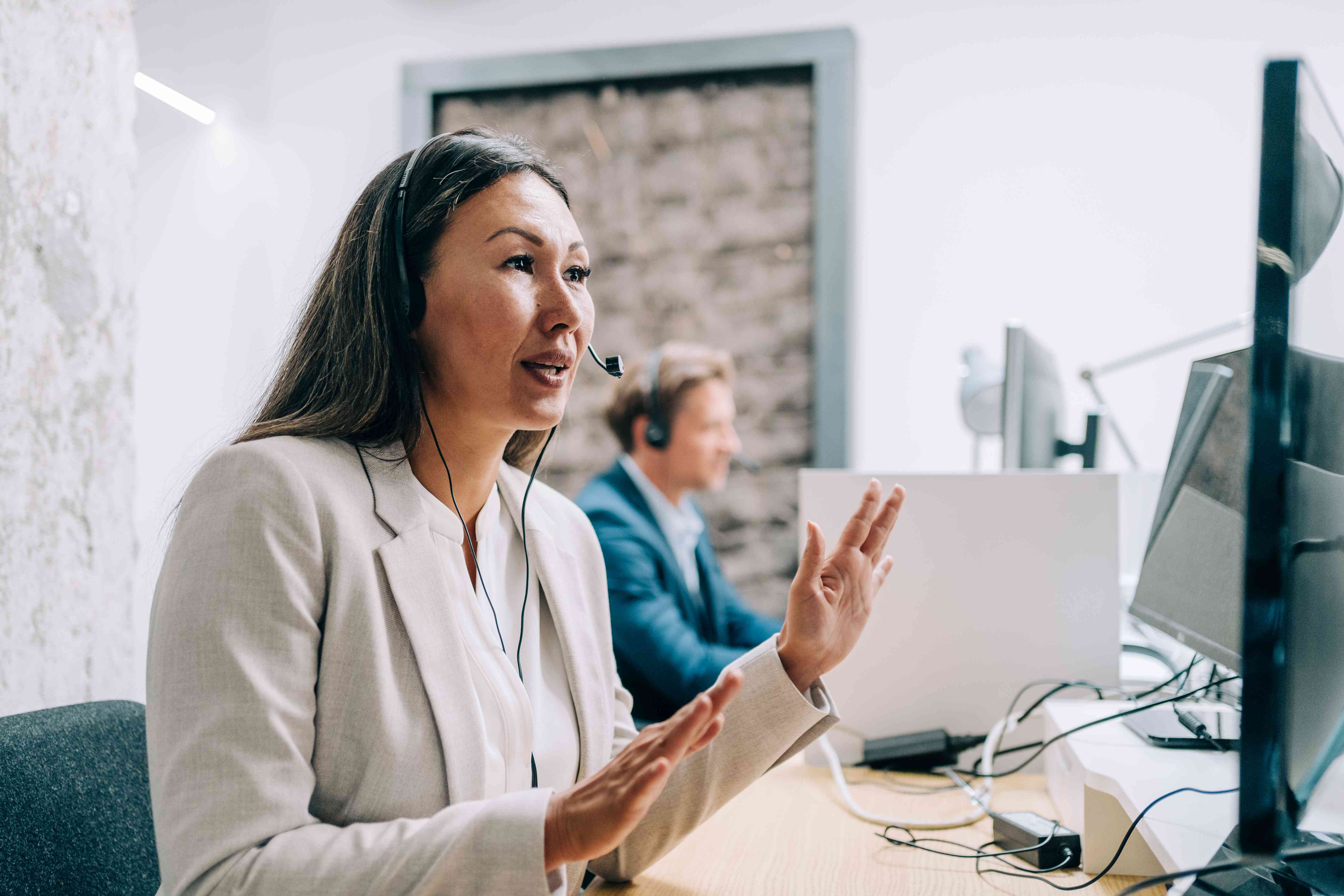 A worker sitting at a desk in a call center with a headset on warm calling a potential client.