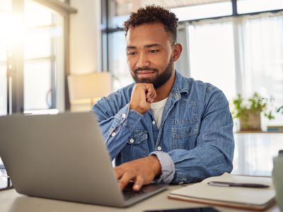 a person sitting in an office in front of a laptop looking intently at the screen 