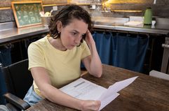 Woman looking at paper statements in a kitchen