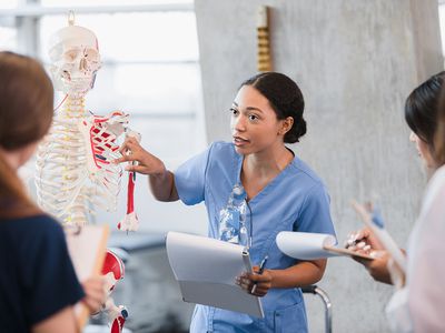 Young woman teaches class on human bone structure medical school