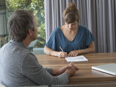 Woman signing papers for a divorce loan