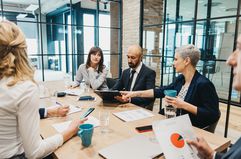 A business team discusses a business plan with diagrams, documents and digital devices in the office.