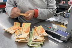 A cashier counts Argentine pesos bills at a supermarket in Buenos Aires while the Argentine peso suffers constant depreciation against the US dollar