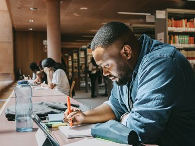 Image shows a student studying in a library. 