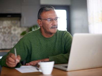 Man looking at his laptop trying to find the best online gold dealers.