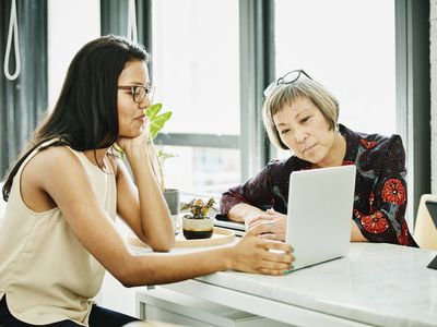 Female financial advisor reviewing data on laptop while meeting with businesswoman in office