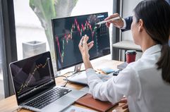 woman at desktop looking at financial charts