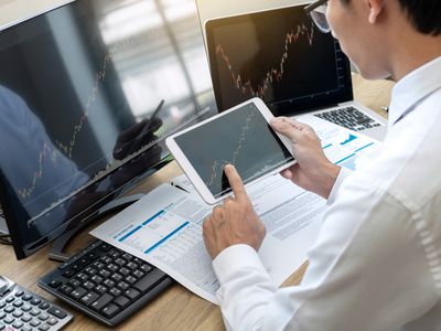 A midsection of businessman using technologies in office with data and charts.