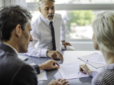 An insurance agent sits across a desk from a couple and explains the length of time, or term, that the policy will cover.