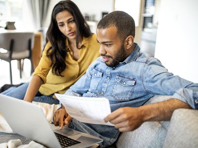 Two people look at a laptop.