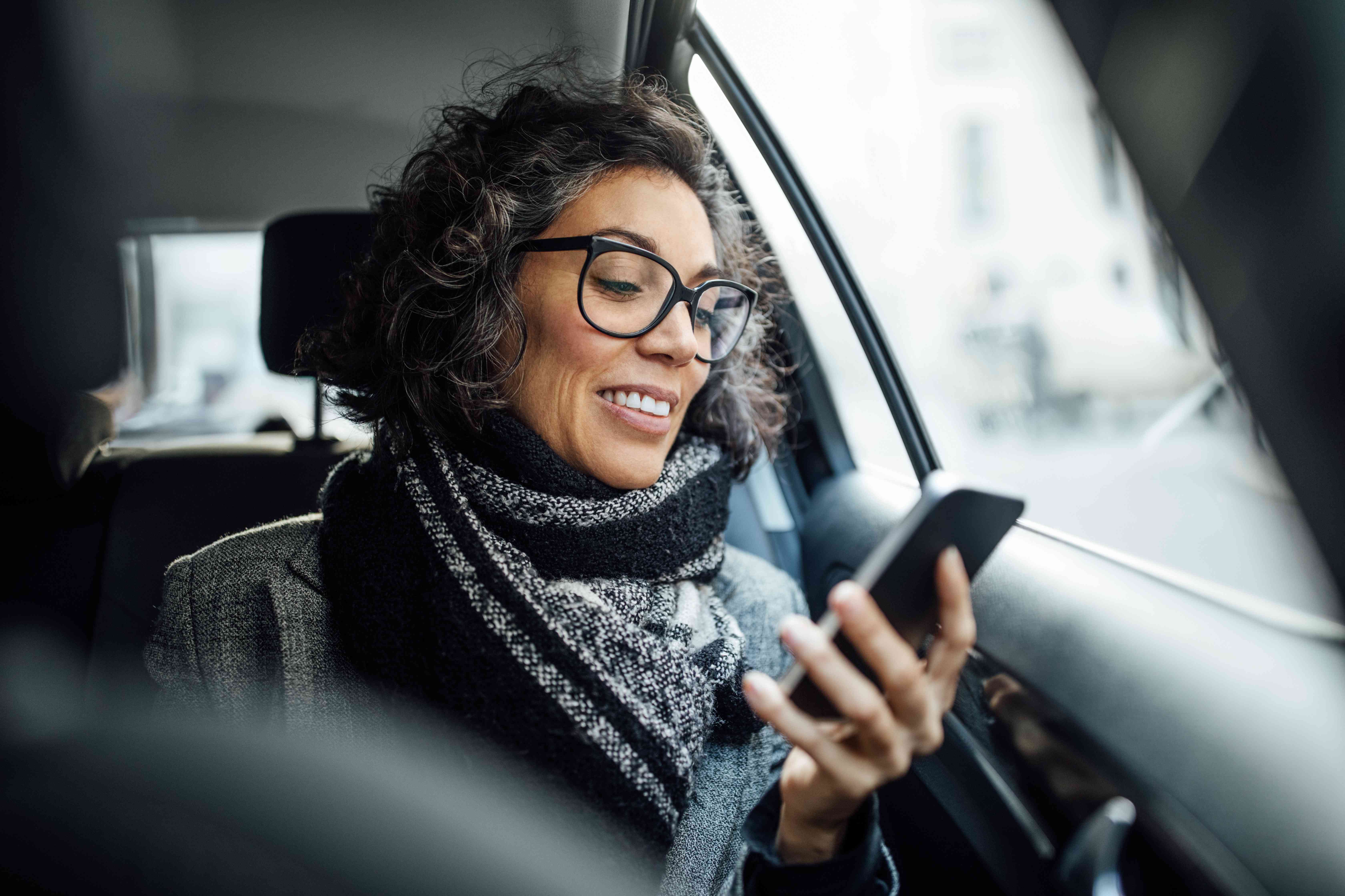 A woman rides in the back seat of a car.