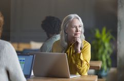 office woman with a laptop in front gazing outside pensively