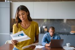 A woman looks concerned as she reads paperwork.